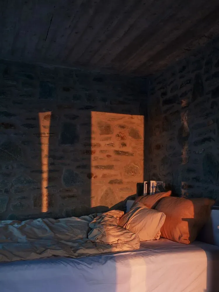 A bathroom with rustic stone walls and natural light streaming in through a window.