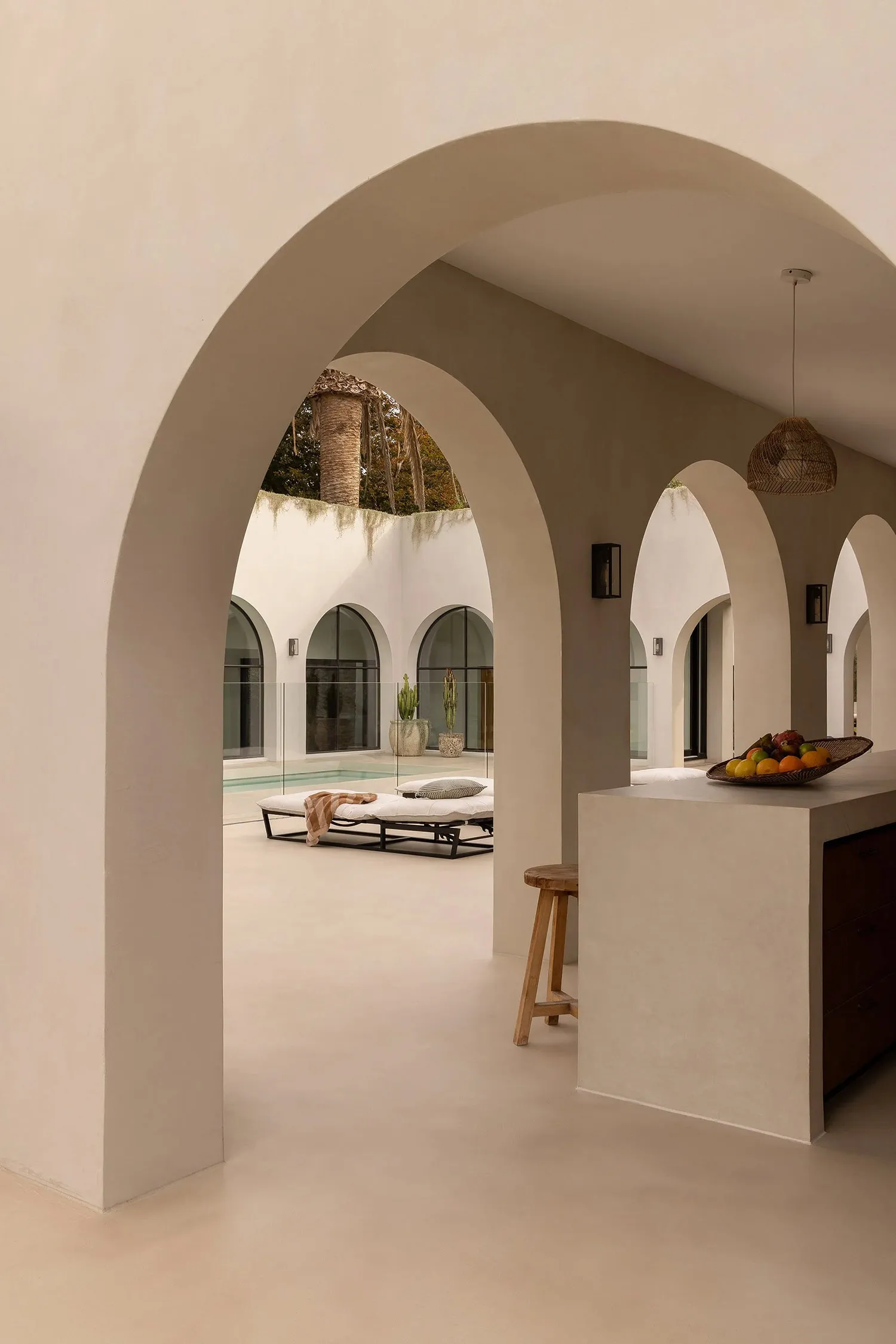 A minimalist residential interior with concrete walls, wooden furniture, and glass elements.