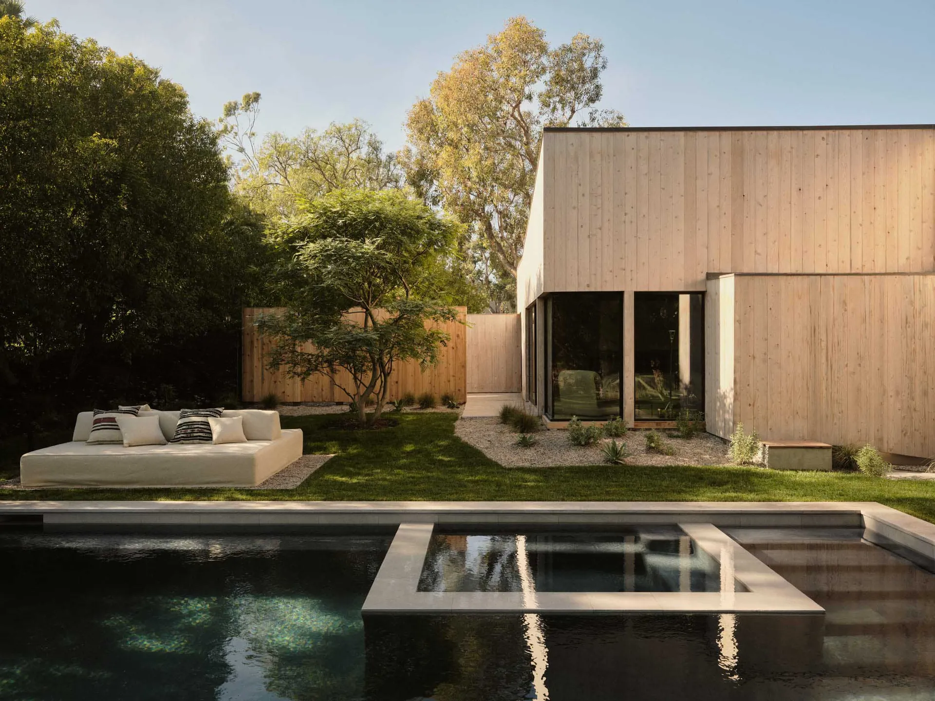 A modern wooden house with a pool and outdoor seating area.