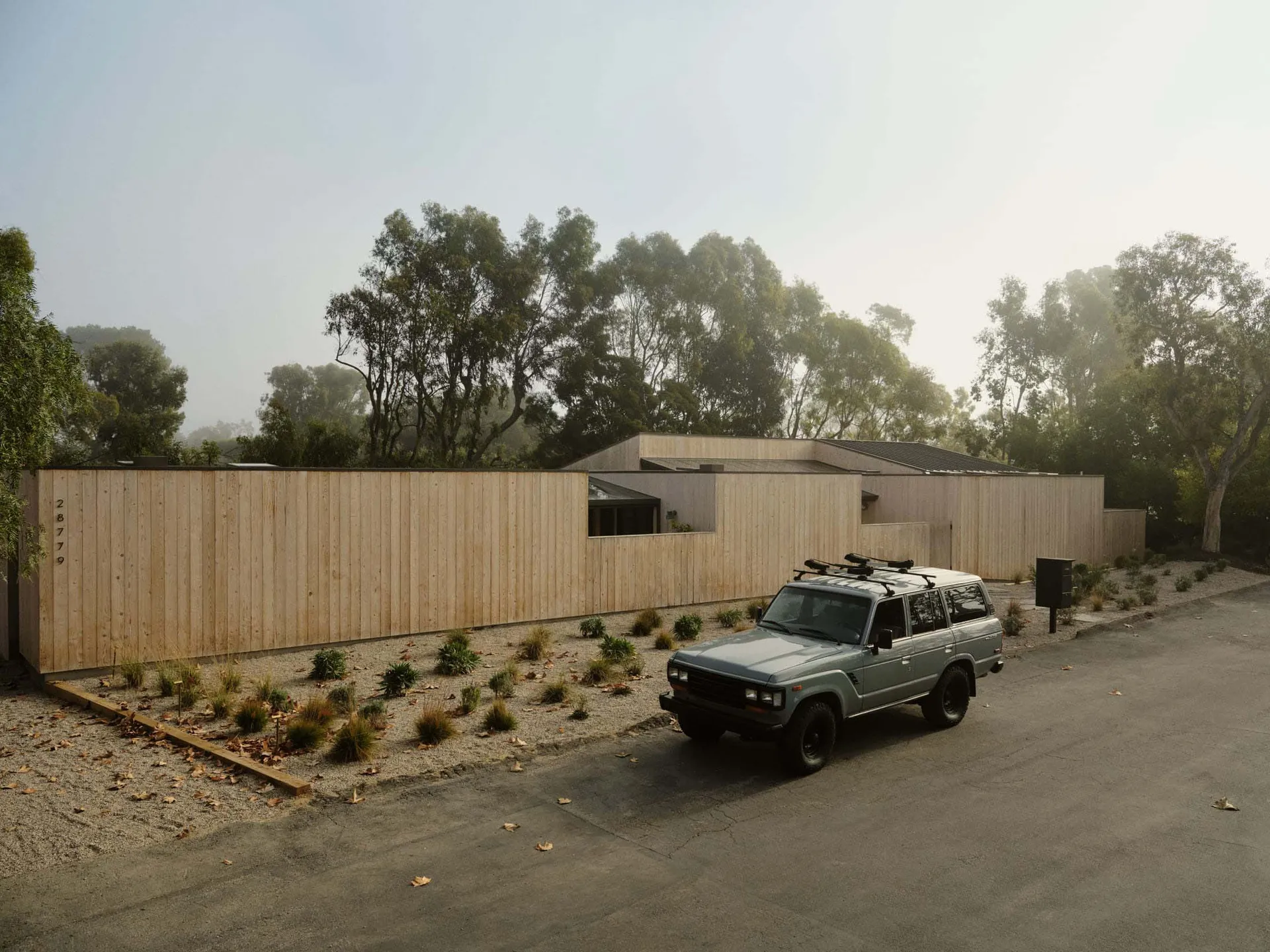 A modern residential exterior featuring a wood-paneled fence and house.
