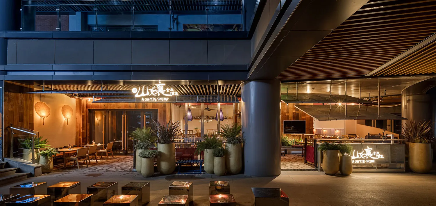 An elegant modern restaurant interior featuring wood, concrete, and metal elements.