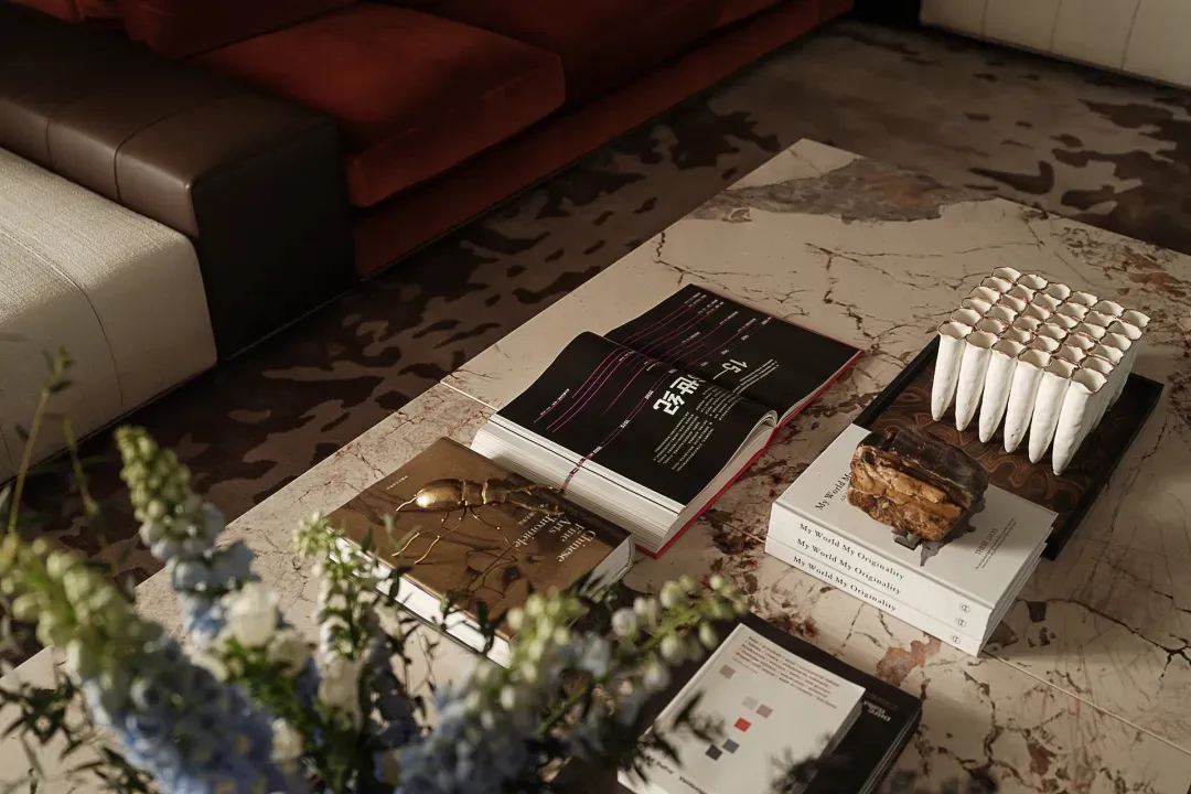 A modern coffee table with a marble surface, books, and decorative items on it.