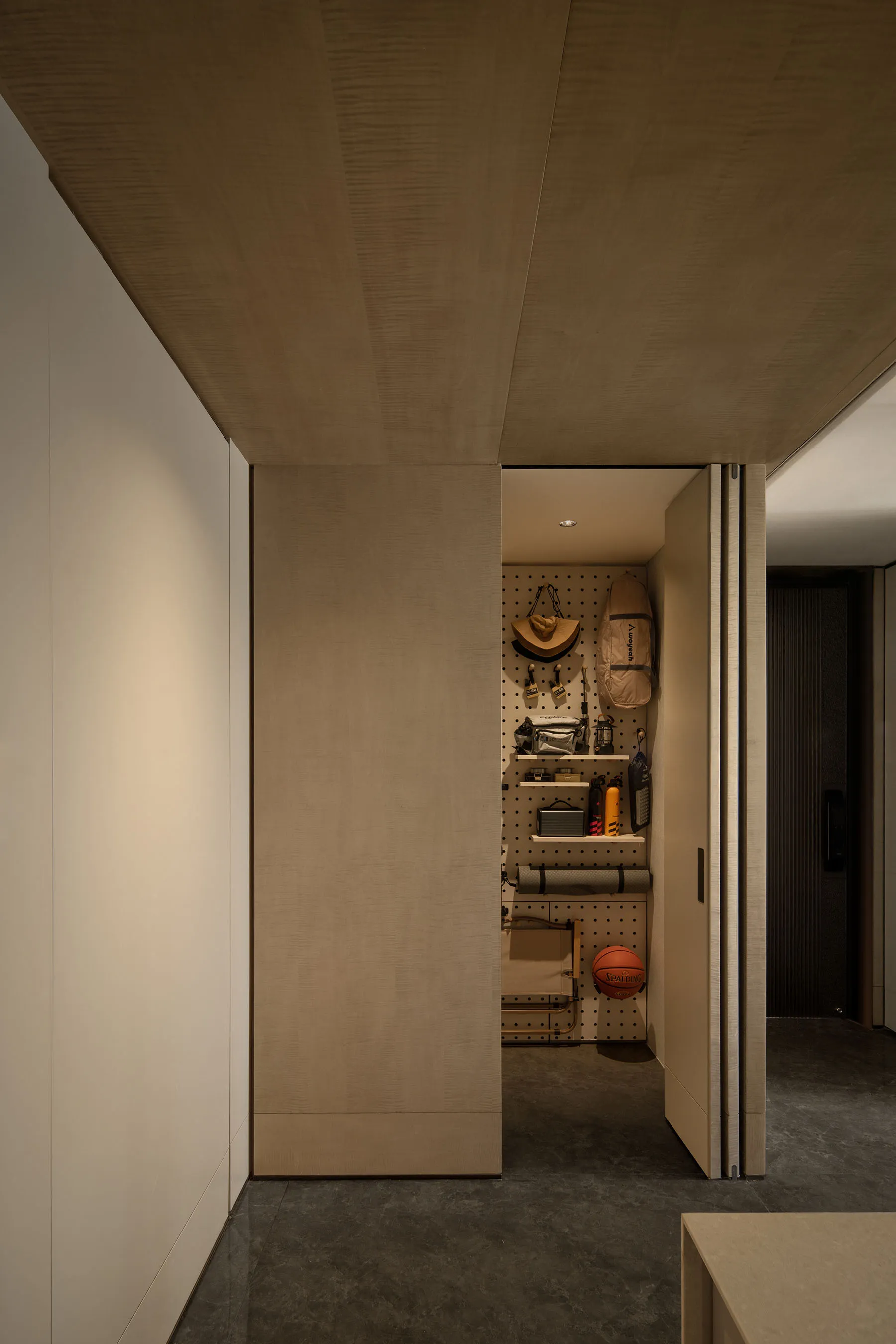 A minimalist closet with wooden walls and a pegboard for organizing items.