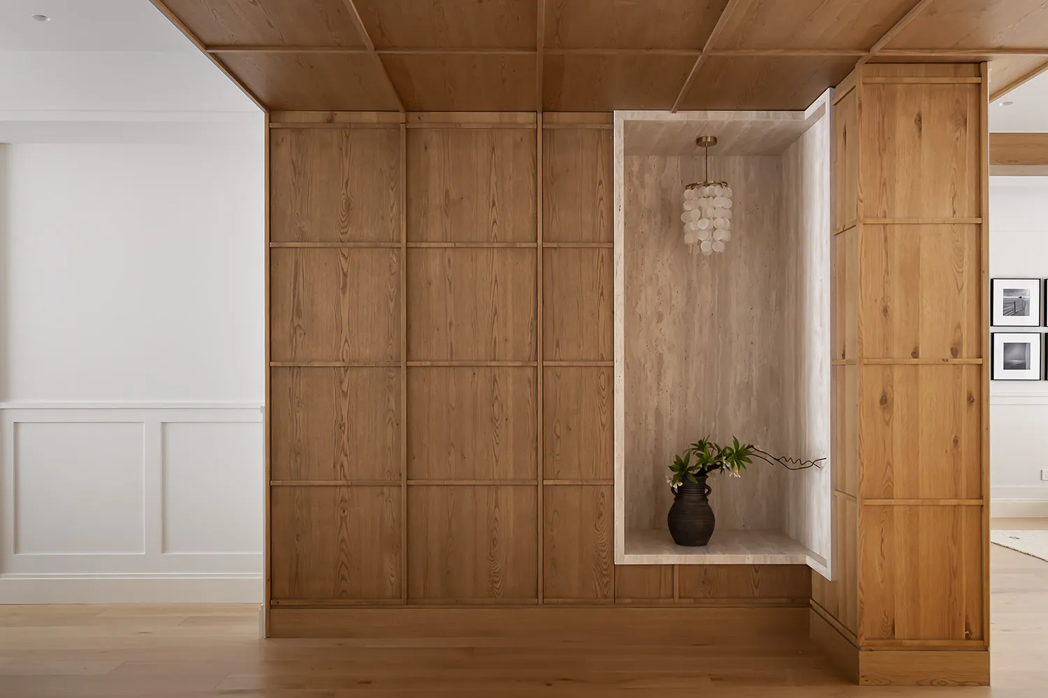 A living room featuring wooden walls, built-in shelves, and marble accents.