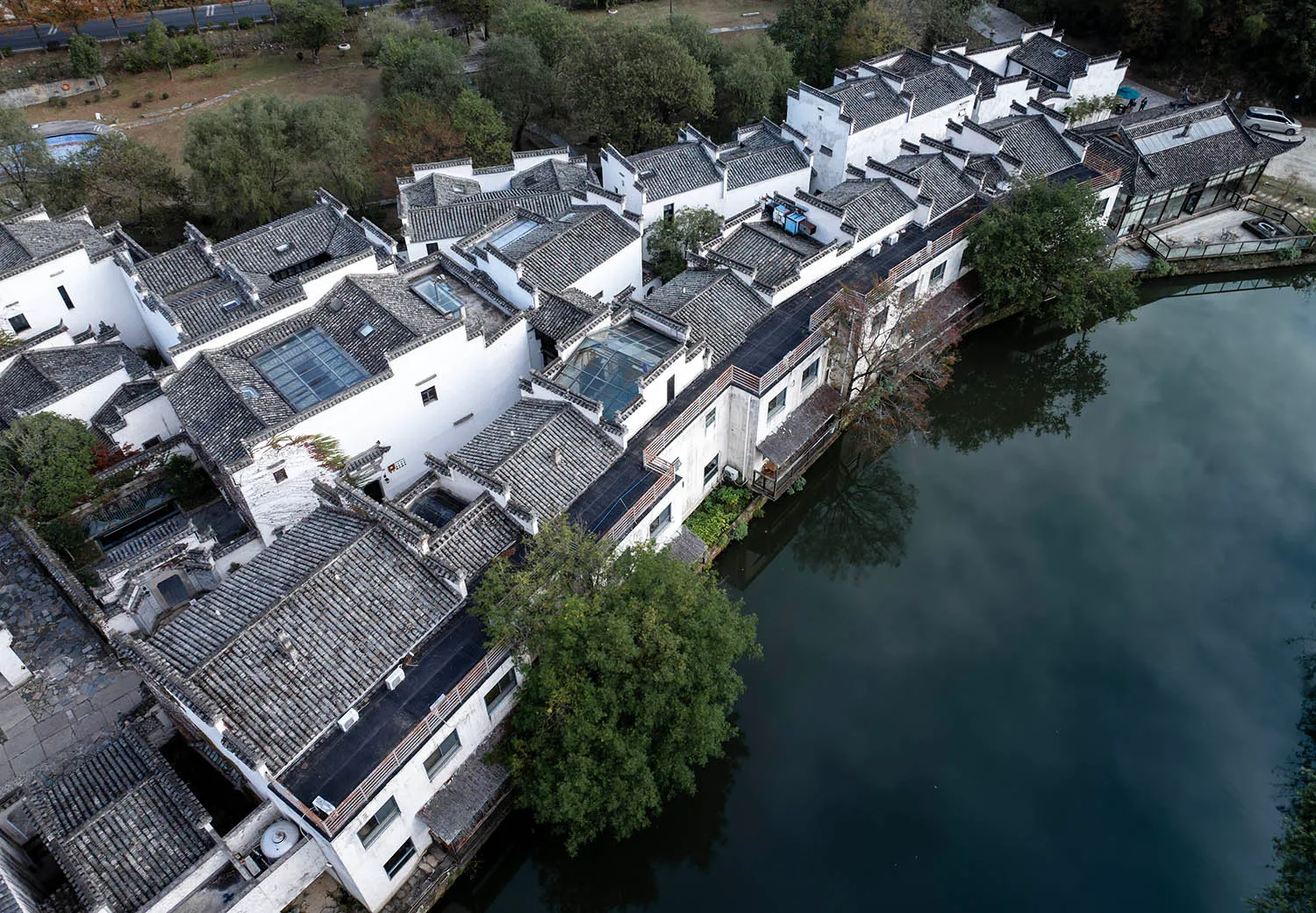 白色粉刷牆面與陶土瓦屋頂的住宅建築,四周環繞水景與綠意。