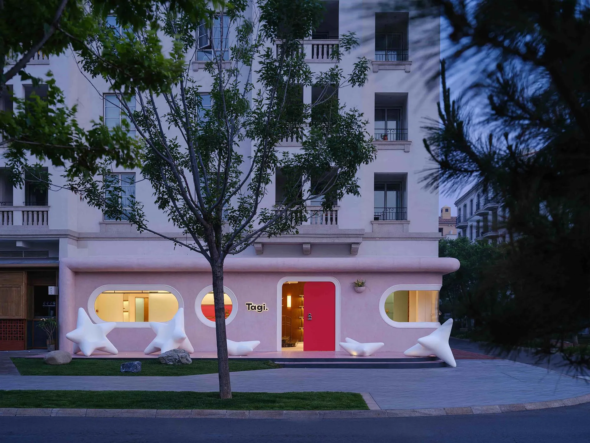 A modern architectural storefront with a concrete facade and large, artistic wooden doors.