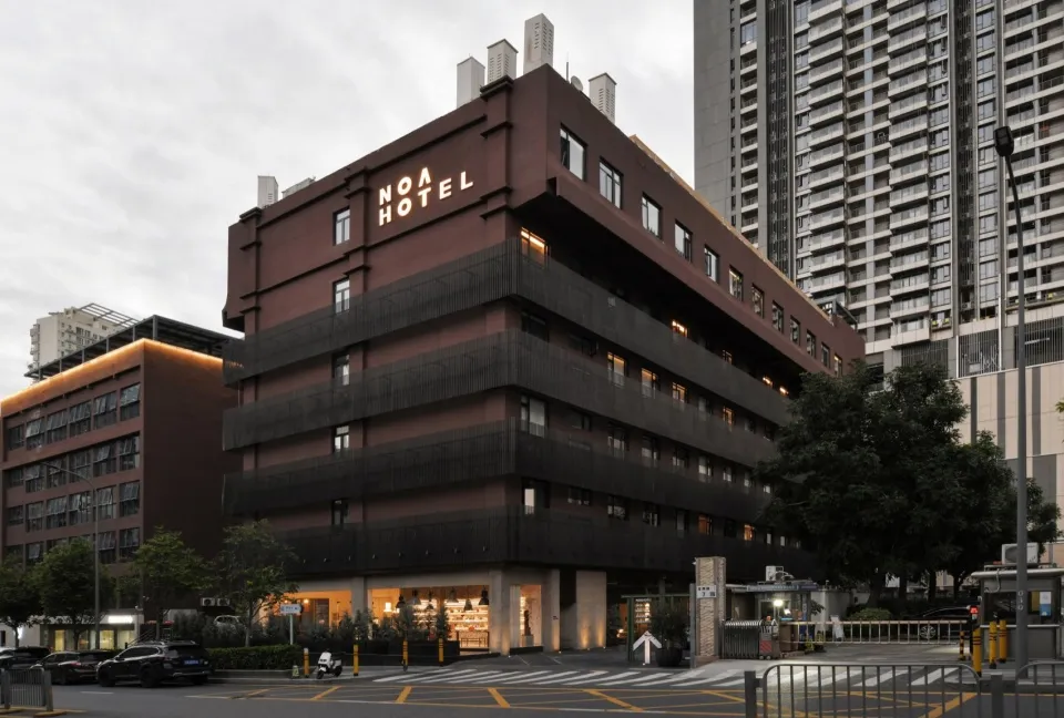 一座擁有磚牆外觀的現代旅館建築,搭配燈光照亮的招牌。