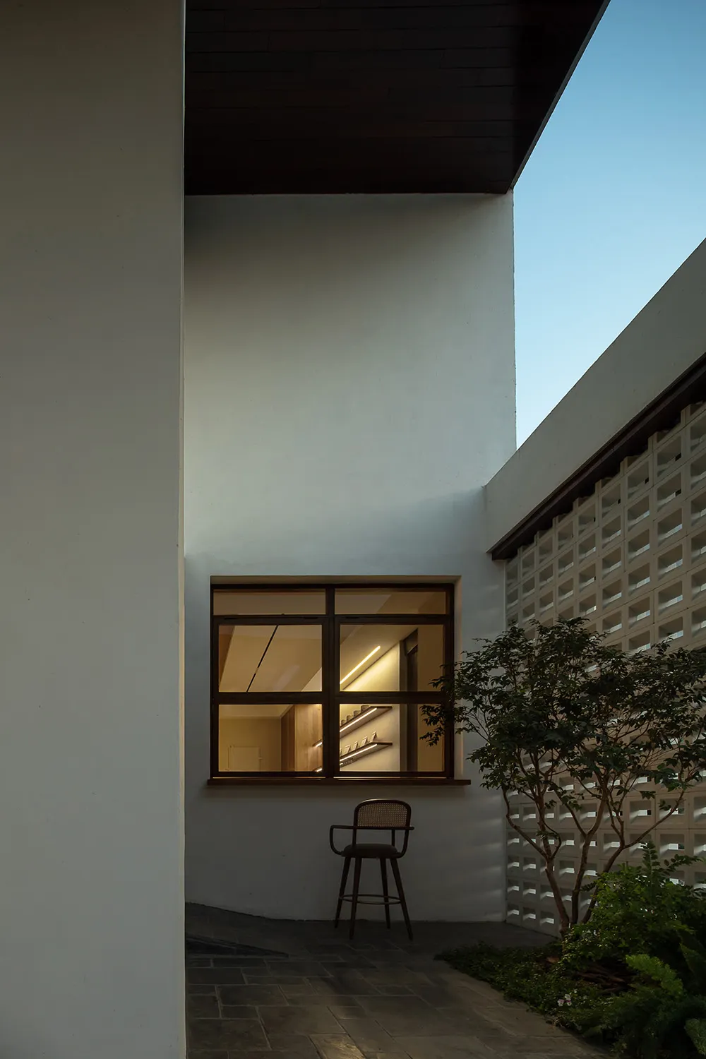 Concrete residential building entrance with a window emitting warm light.