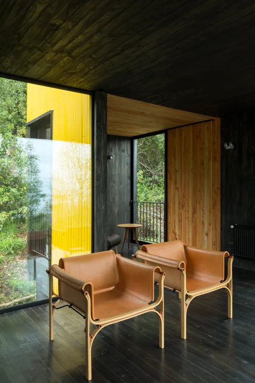 A modern interior design featuring a living room with leather furniture and a dark wooden floor.