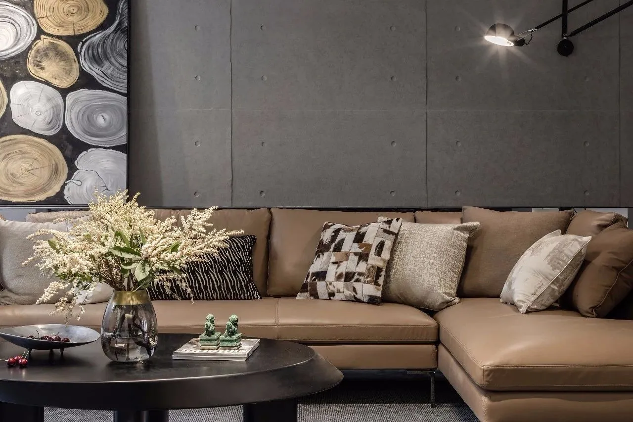 Modern living room featuring a fabric leather sofa, decorative cushions, and a coffee table with a vase of flowers and cherri