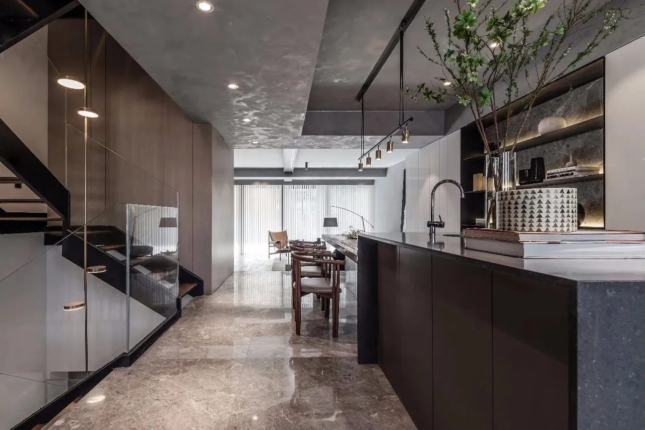 Modern kitchen with marble countertops and floor, featuring minimalist design elements and sleek, black accents.