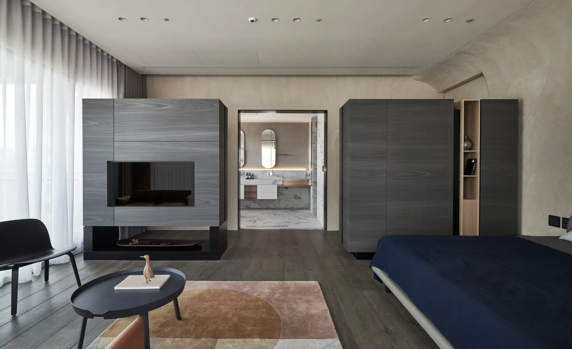 A modern bedroom suite featuring minimalist furniture and a large, dark-colored cabinet.