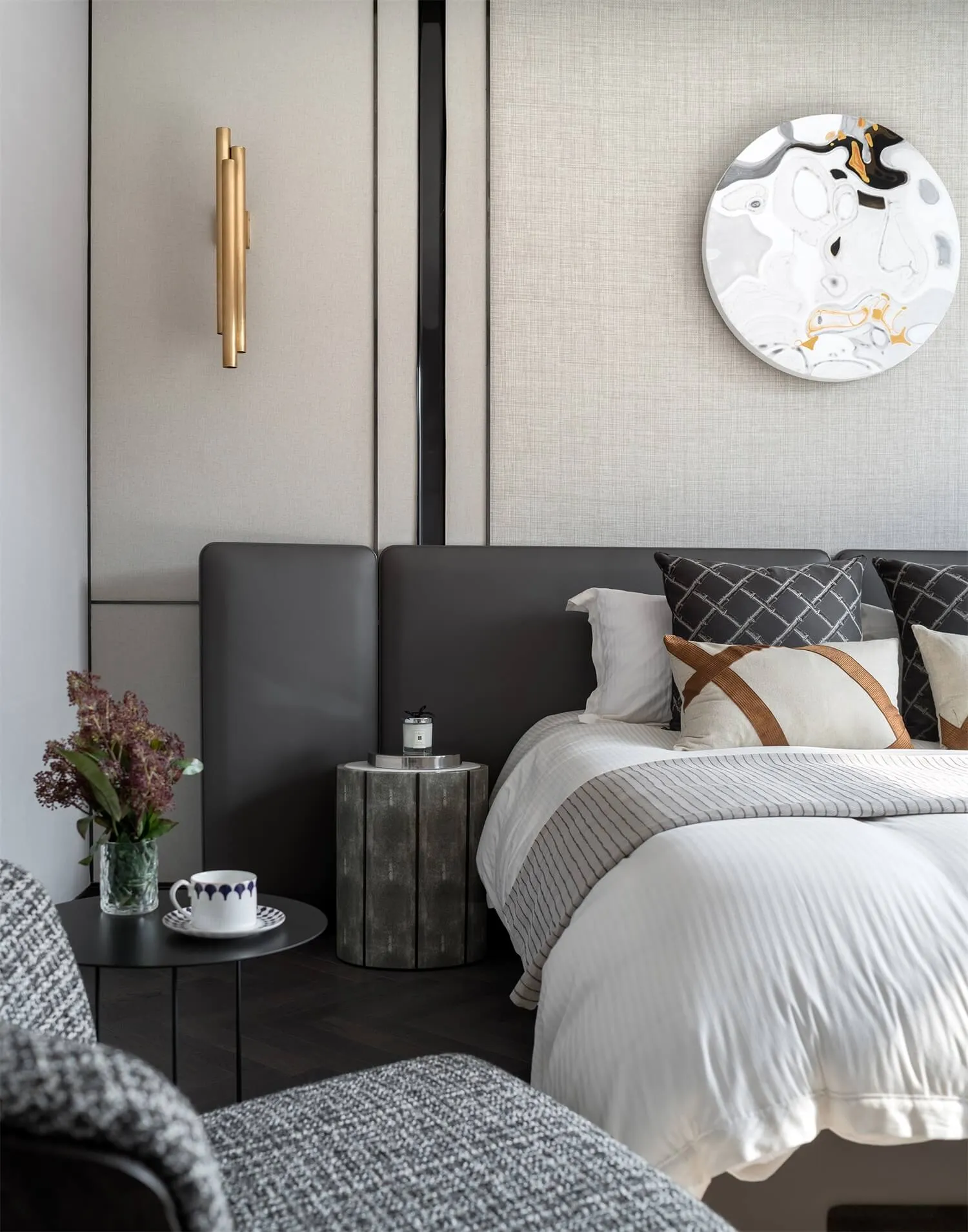A modern bedroom featuring a textured leather headboard, white bed linen, and decorative cushions.