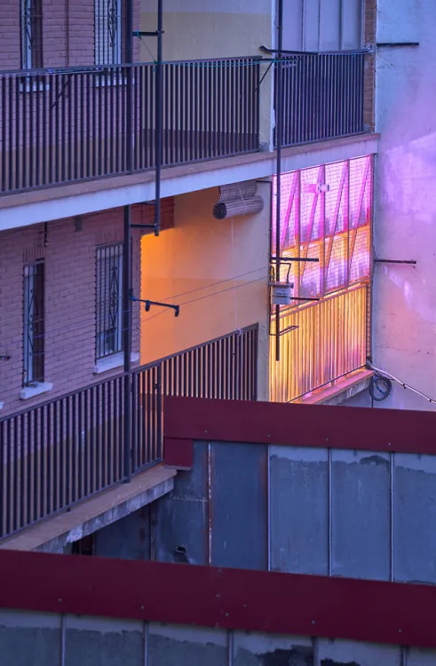 A modern building with metal railings and balconies illuminated at night.