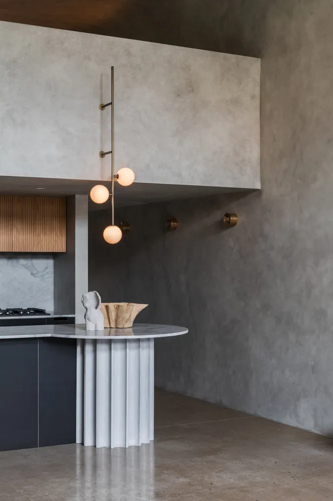 A modern kitchen featuring metallic pendant lighting and a sculptural centerpiece.