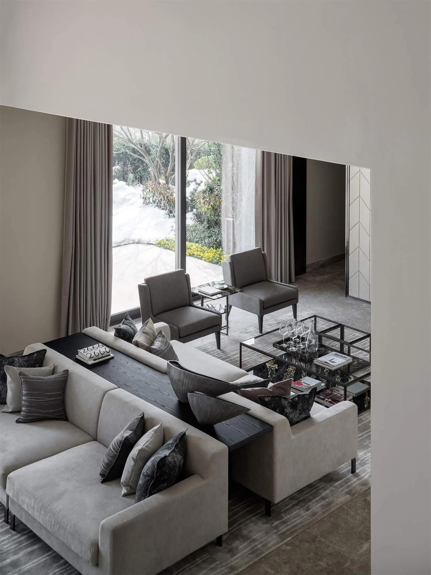 A modern grey living room with a comfortable sectional sofa adorned with dark grey cushions and decorative pillows, accompani