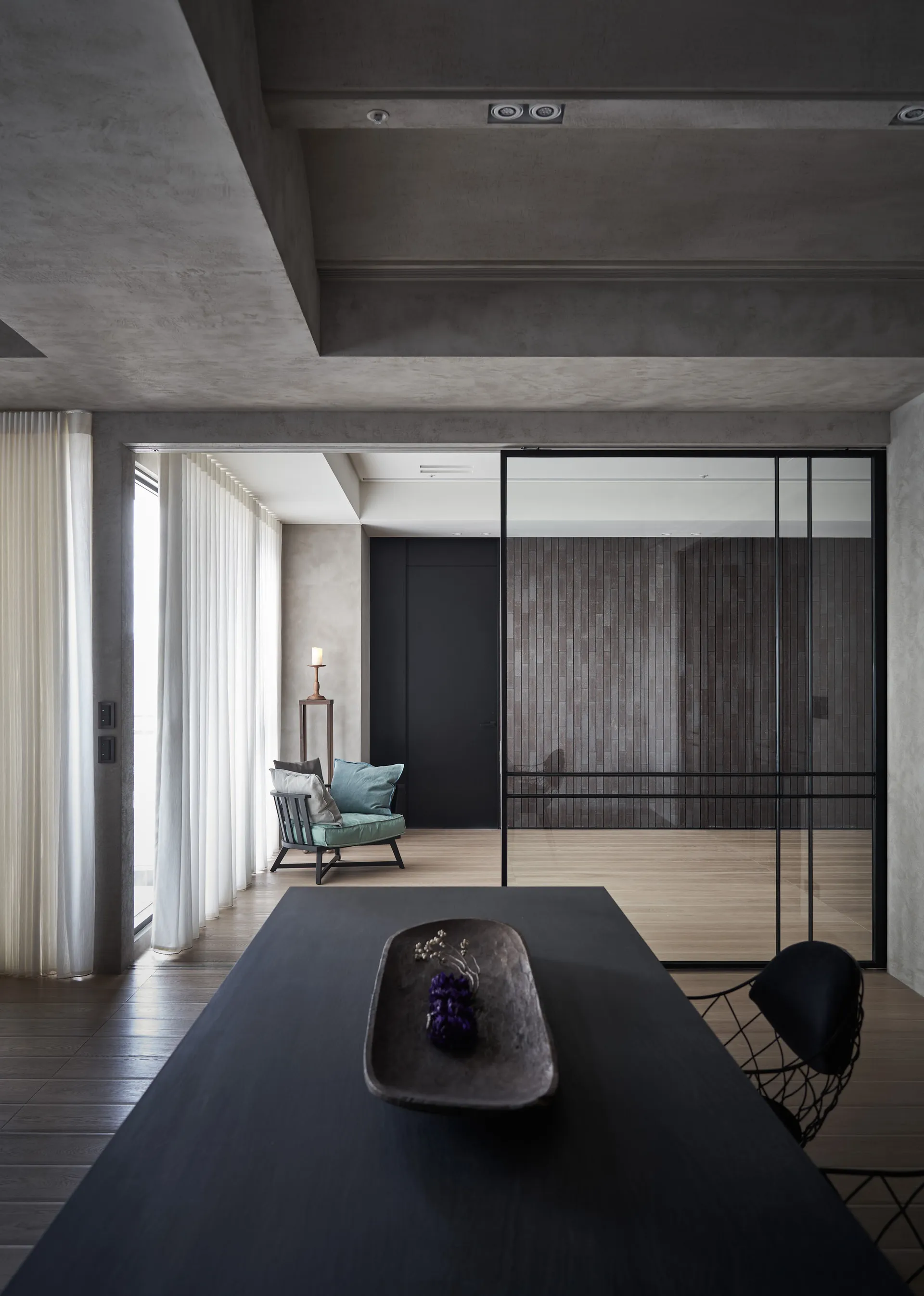 A modern living room with concrete curtains, wooden flooring, and a minimalist design.
