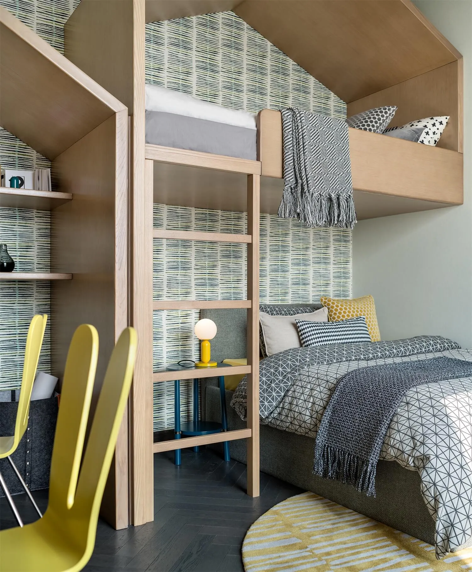 A modern residential interior featuring a bunk bed with wooden frames and printed textiles, a single bed with geometric patte