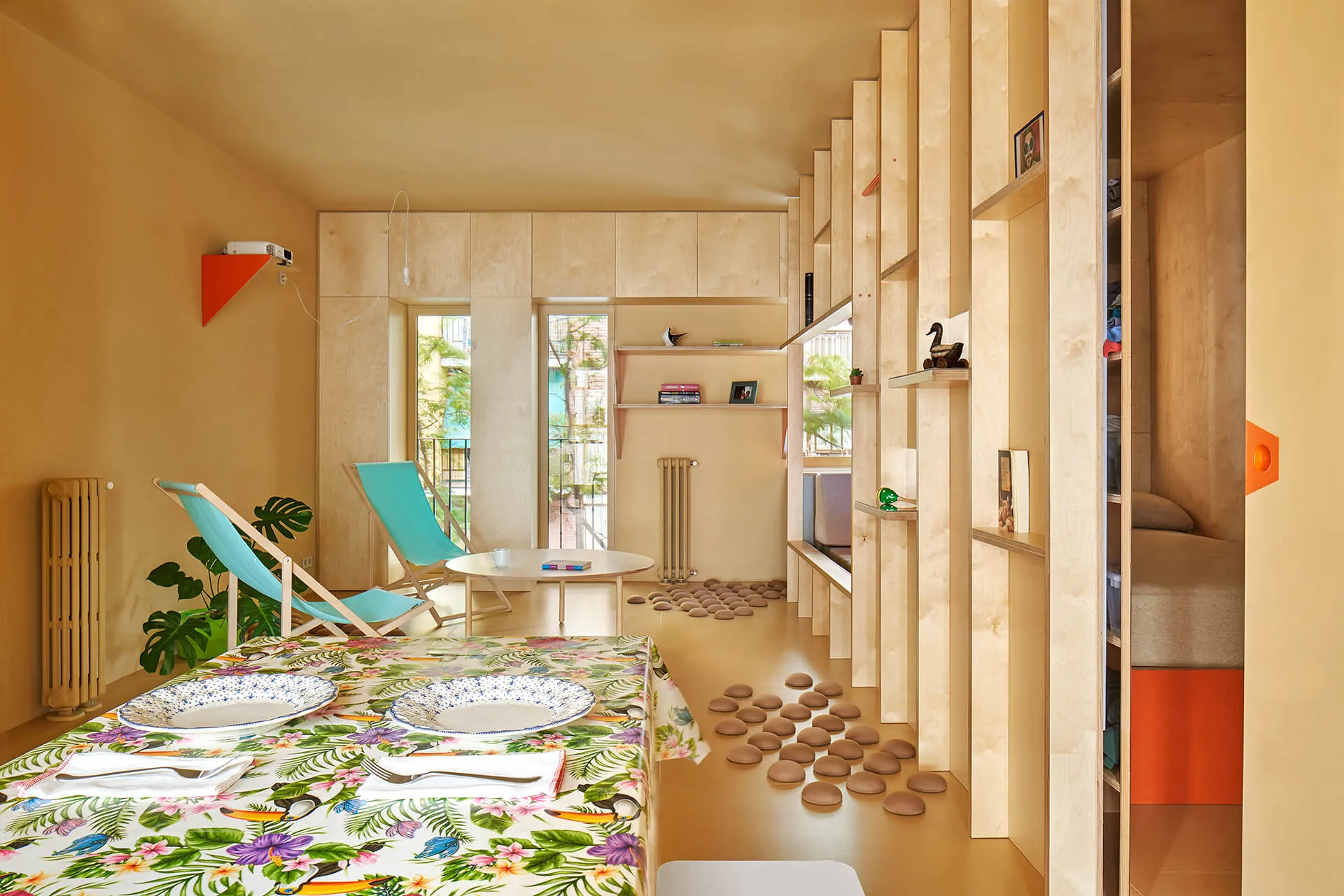 Modern small apartment with wooden plywood interior, featuring a dining table and chairs, a small table with a bird statue an