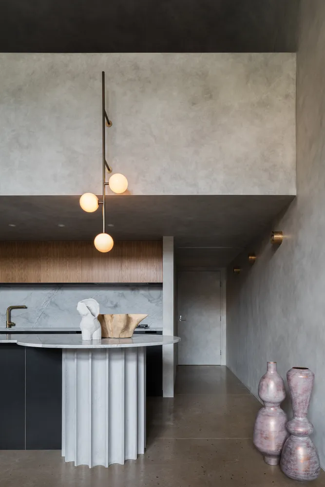 A modern residential kitchen featuring a marble countertop and concrete elements.