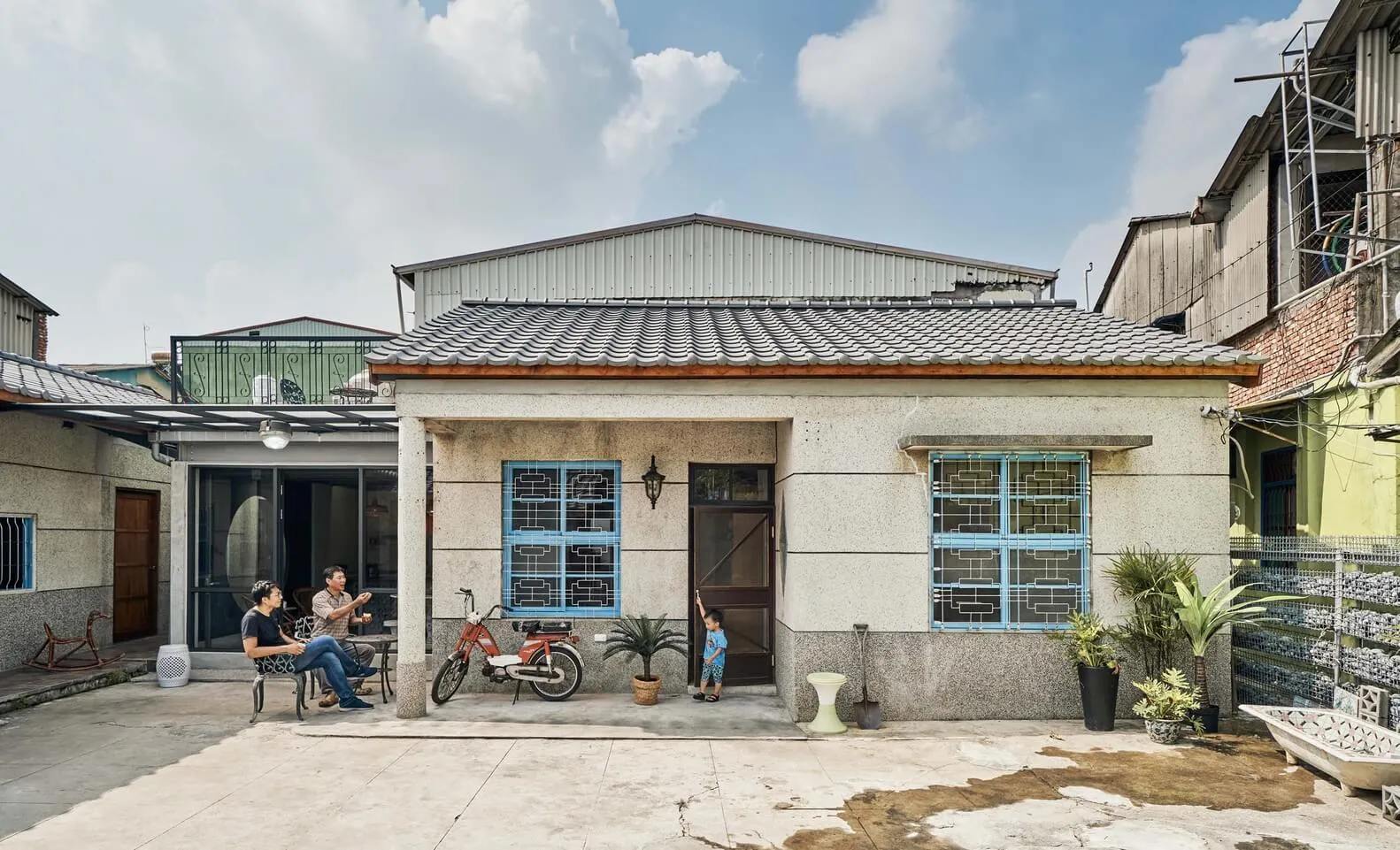 一座現代住宅外觀漆以淺色調，呈現混凝土質感，搭配山牆屋頂與小型門廊