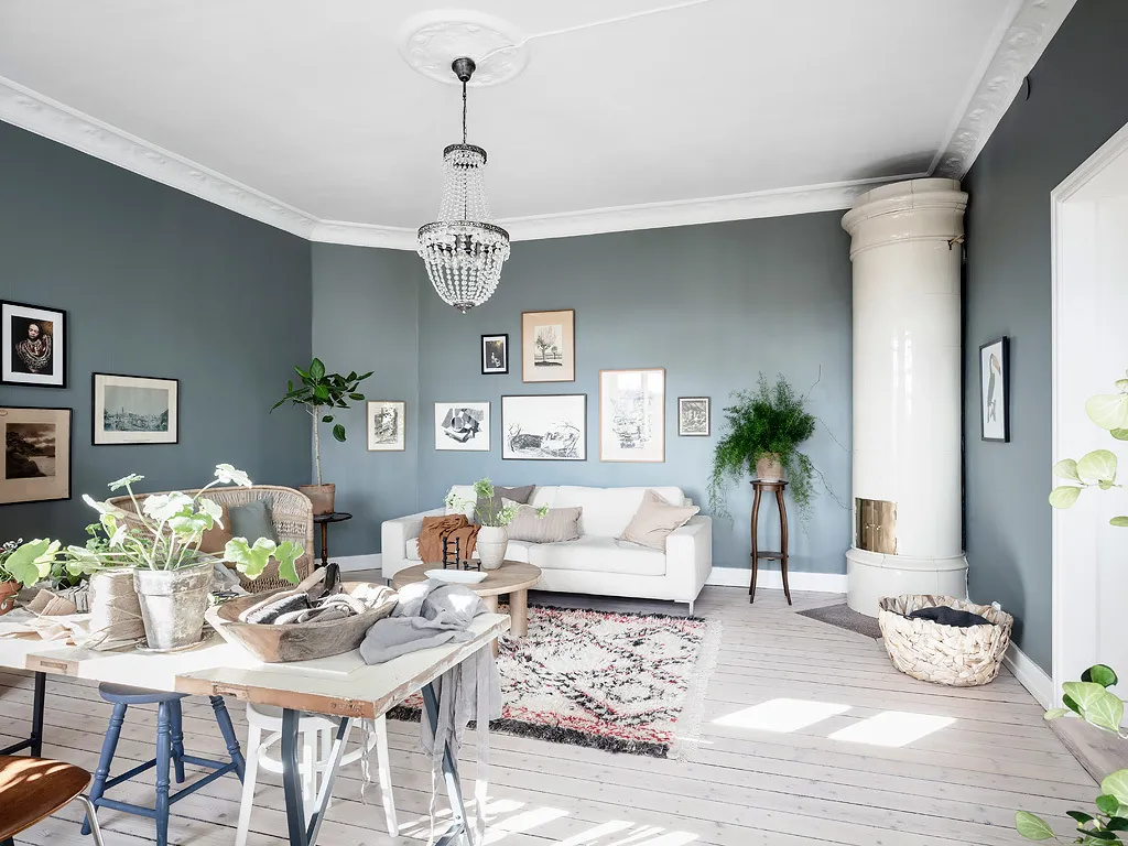 A modern Scandinavian living room with a white couch, gallery wall, and white fireplace.