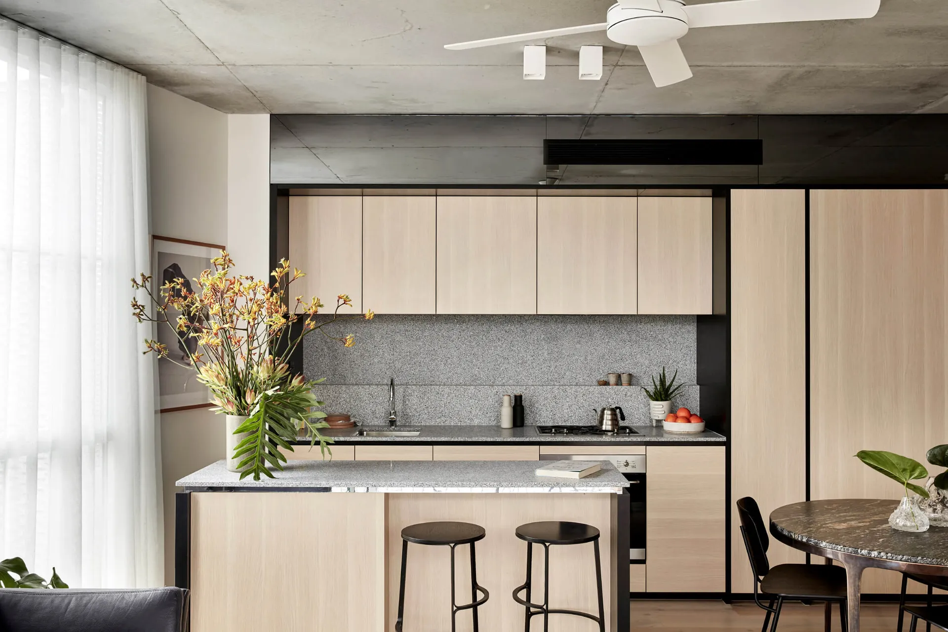 A minimalist kitchen with wooden cabinets, granite countertops, and a central island.