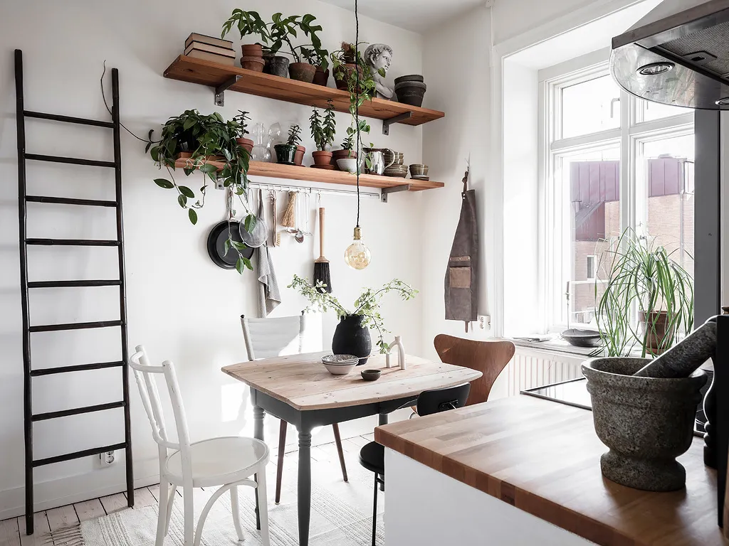 A Scandinavian-style kitchen featuring wooden furniture, glass vases, and metal hardware.