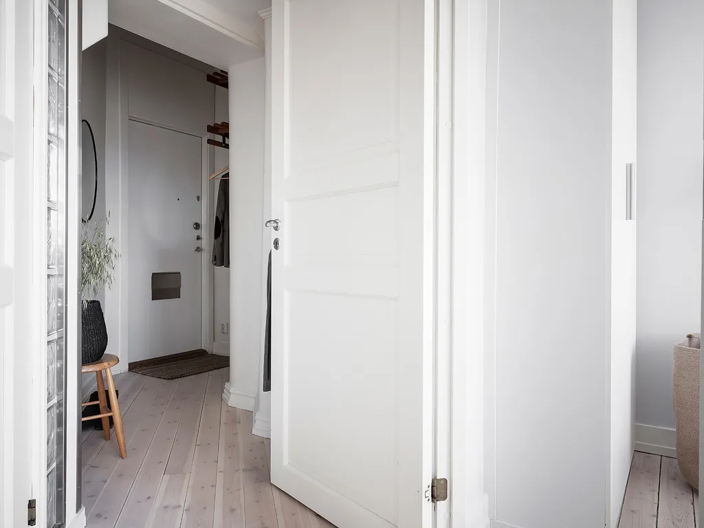 A minimalist interior with white porcelain and wooden flooring and doors.