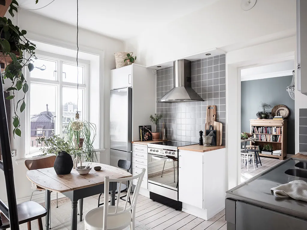 A modern, minimalist kitchen featuring white cabinetry, stainless steel appliances, and a white wooden floor.