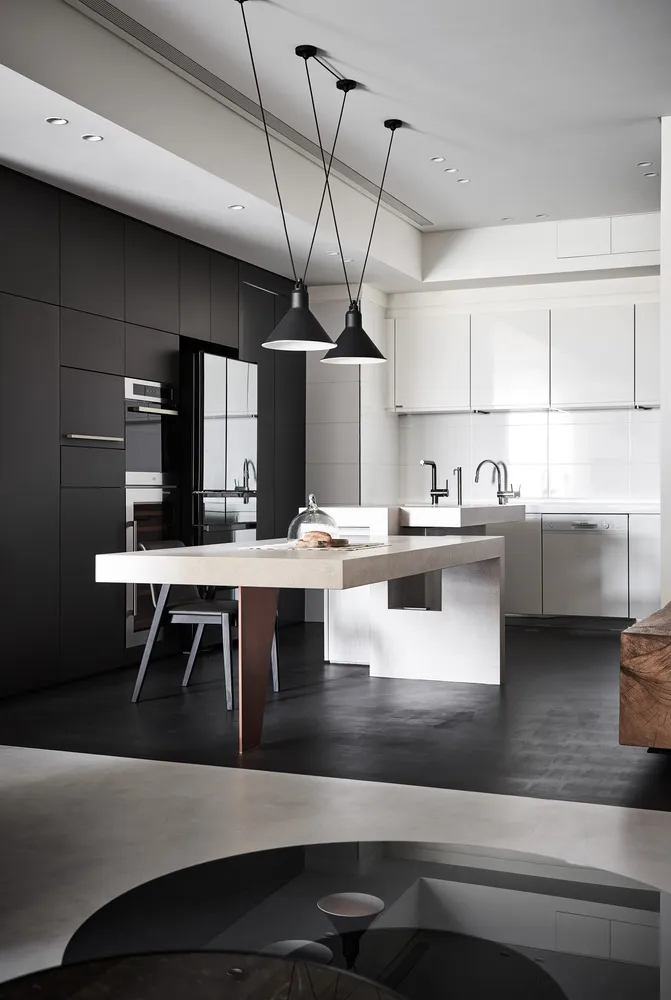 A modern kitchen featuring a concrete island with pendant lights hanging overhead and a sleek, minimalist design.