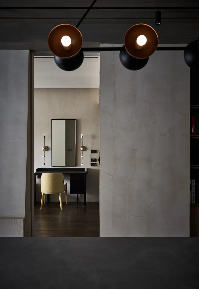 Contemporary living room with minimalist design featuring textured concrete walls and floor, black accents, and a single yell