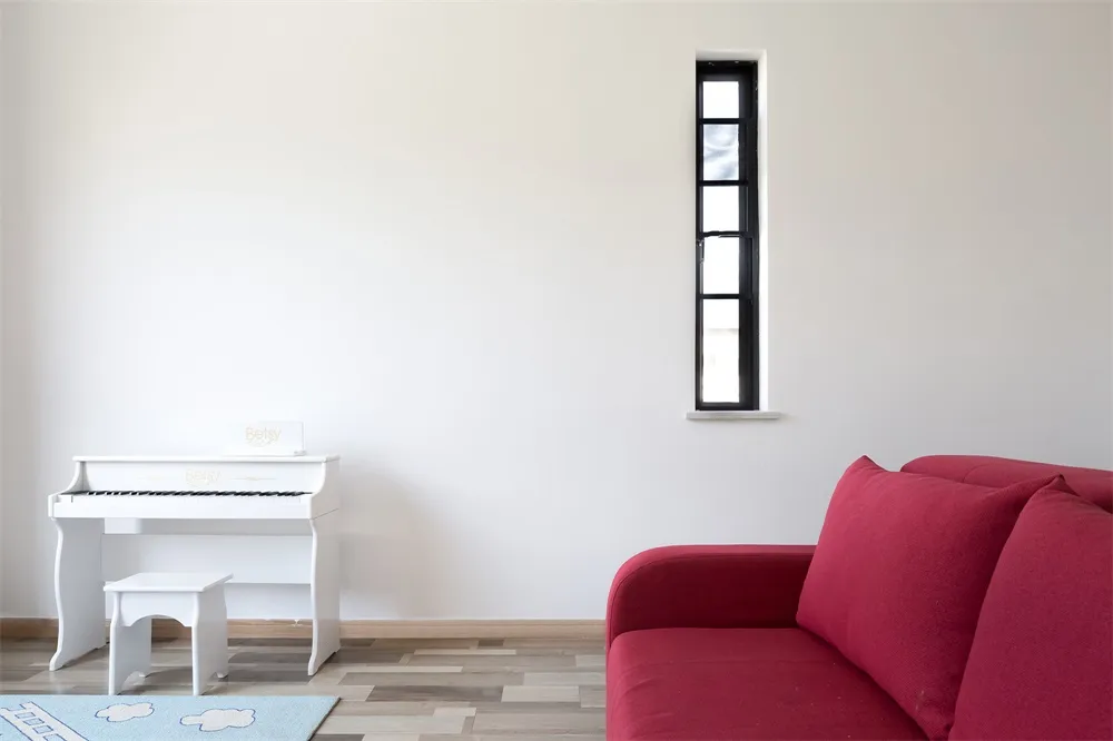 Modern living room with a red sofa, white piano, and wooden flooring.