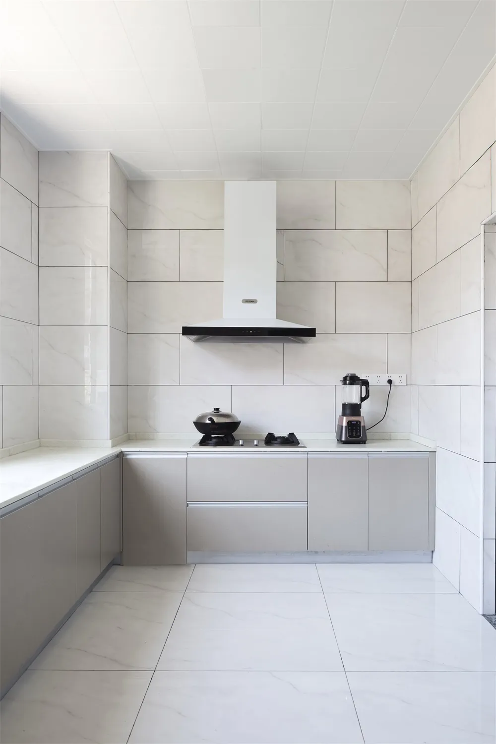Modern minimalist kitchen with white marble countertops and backsplash, featuring sleek cabinets and stainless steel applianc