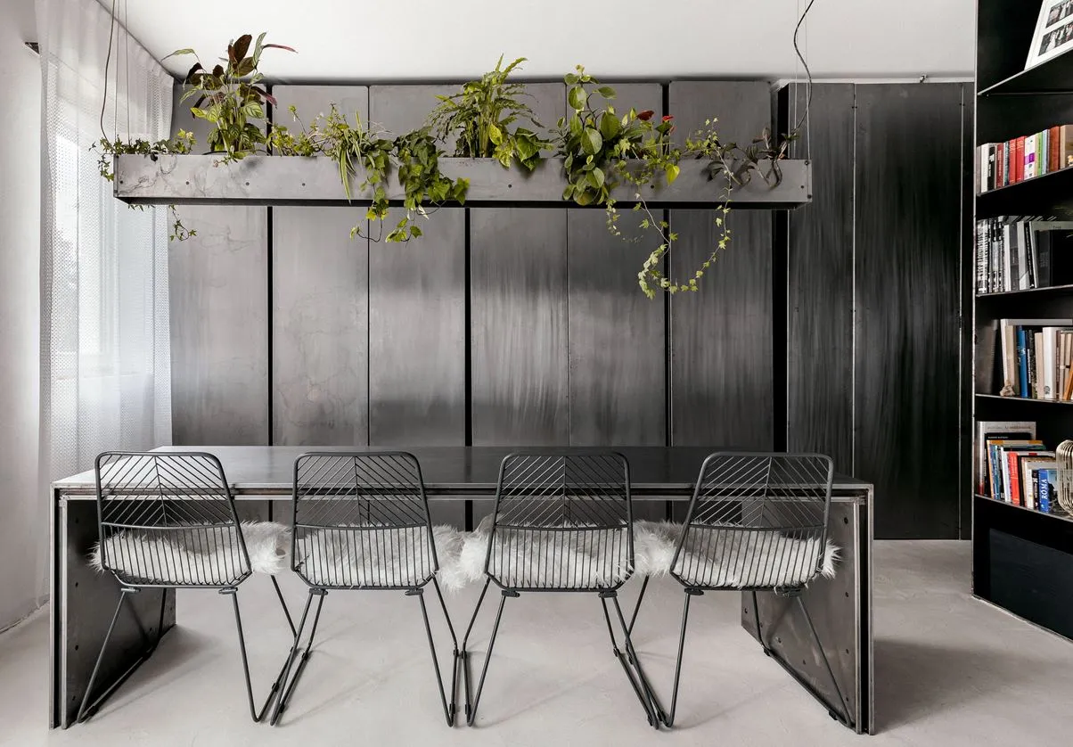 Industrial dining room featuring metal furniture with white cushions and a wall-mounted metal shelf with hanging plants.