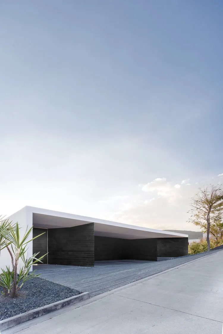 Modern minimalist house with white concrete roof, black architectural elements, and minimalist design.