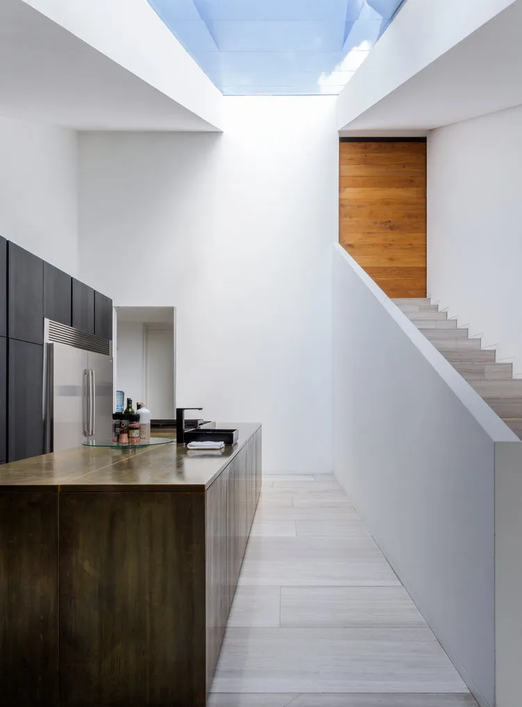 A modern minimalist kitchen with metallic finishes and white tiled flooring.
