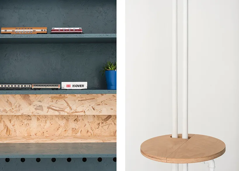 A minimalist interior design featuring a wood shelf with a blue plant pot and model trains.