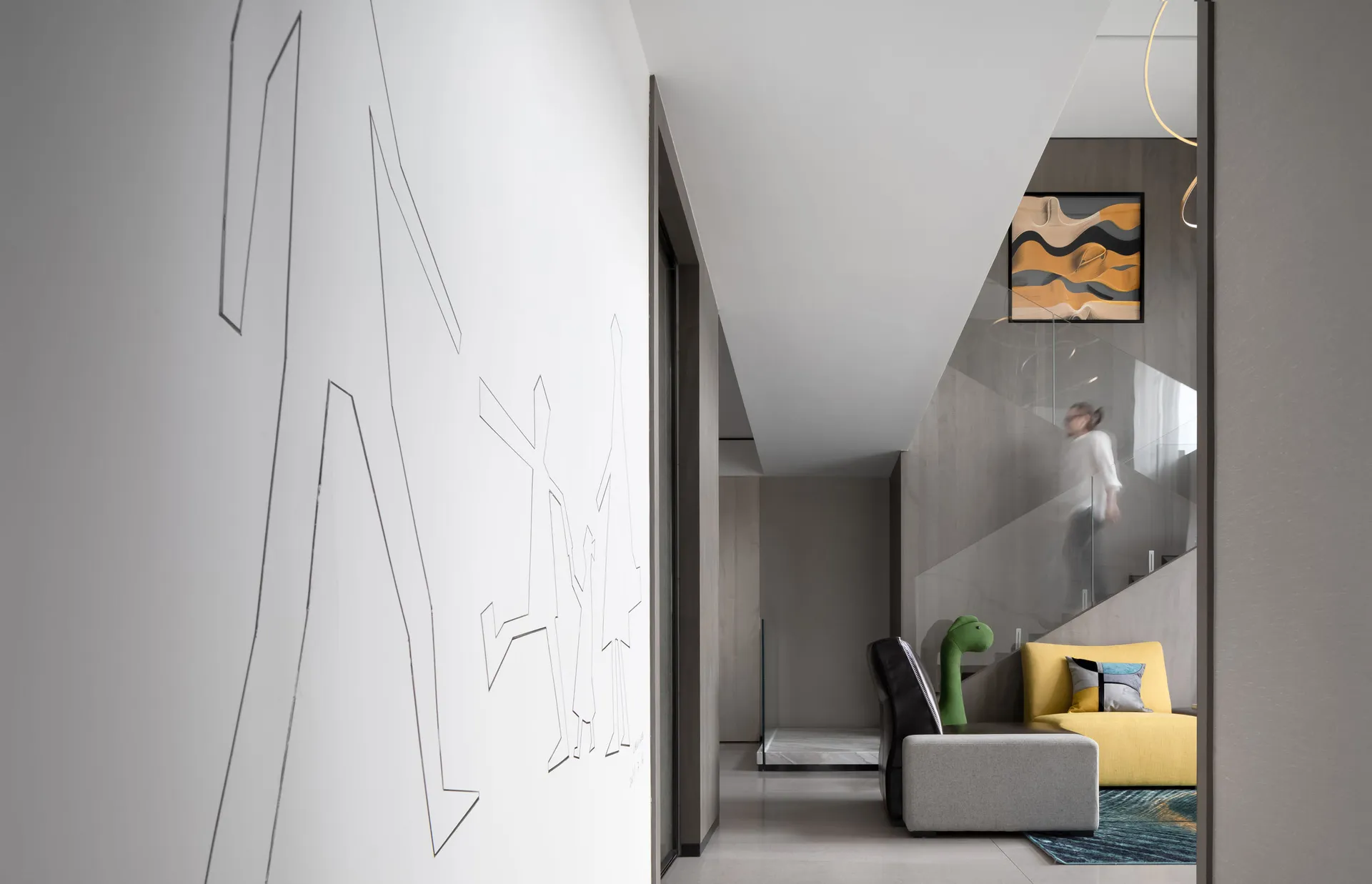A modern living room with concrete flooring, a yellow sofa, and a white wall with abstract art.