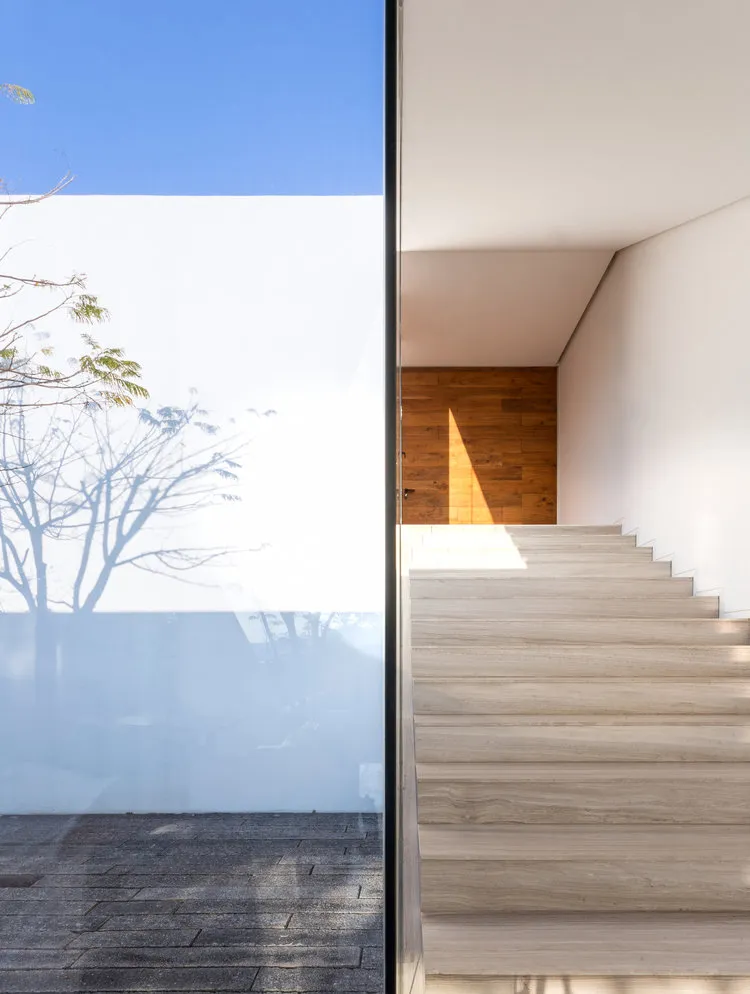 Staircase with glass walls, white walls, and wood floor, leading to a wooden door.