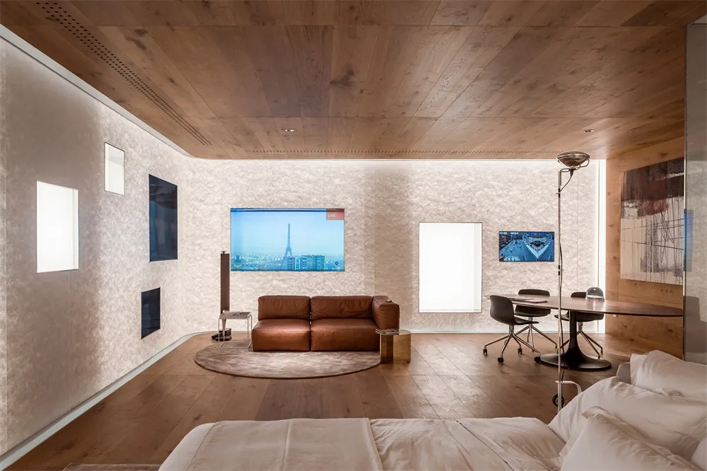 Modern living room featuring a cozy brown leather sofa, hardwood floors, and a large screen displaying a cityscape.