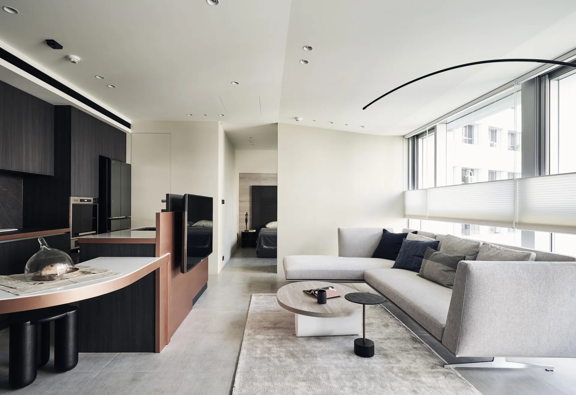 Modern apartment living room featuring concrete floors, glass walls, and textured fabric furniture.
