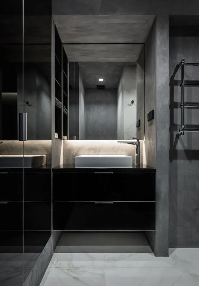 Modern bathroom featuring a sleek, black vanity with a white square sink, illuminated from behind, and a concrete wall with a