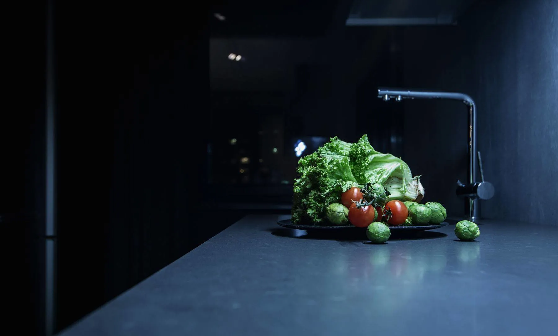 A kitchen scene with a concrete countertop and a plate of vegetables.