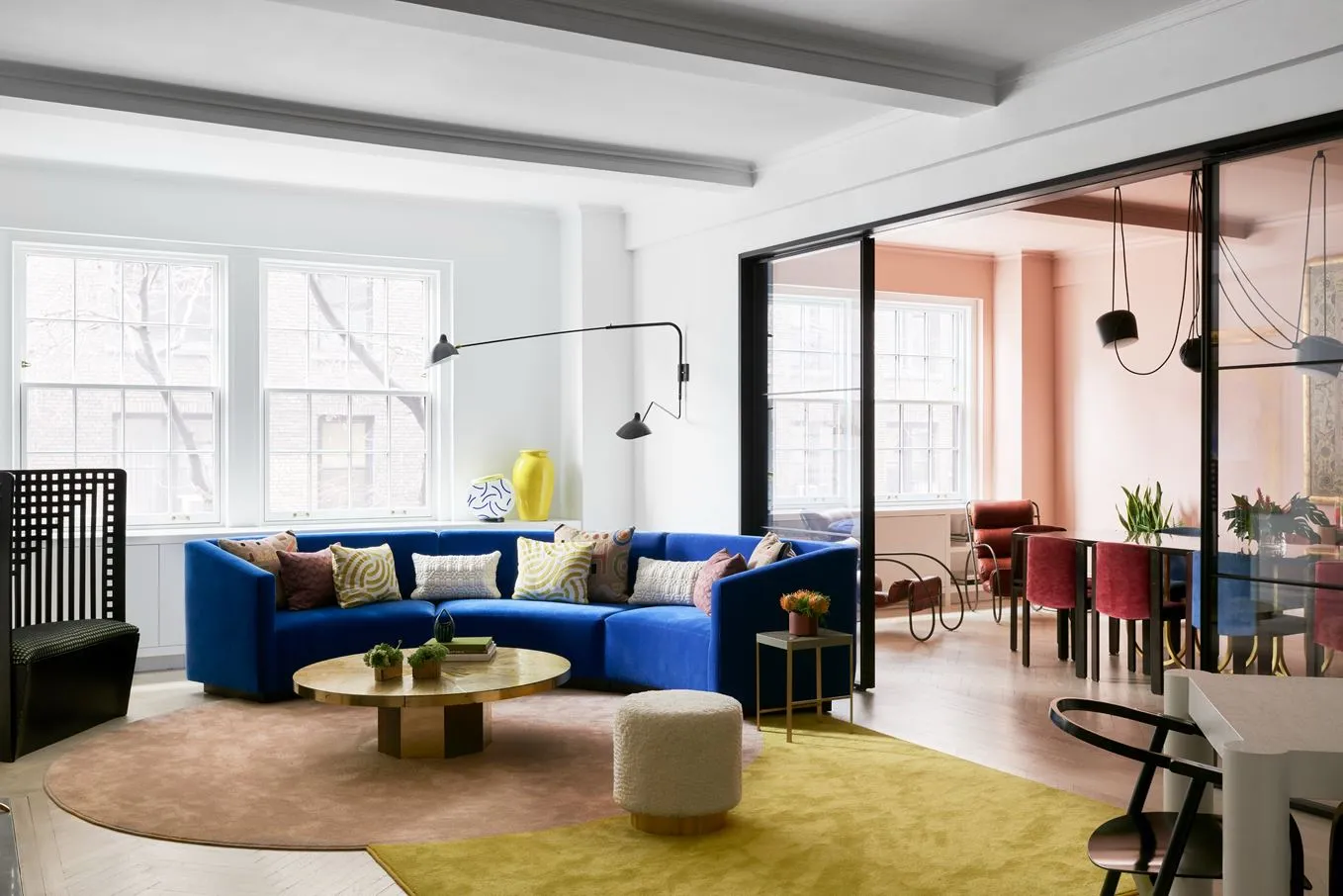 Modern living room with a blue sofa, multiple pillows, a round wooden coffee table, and a yellow carpet