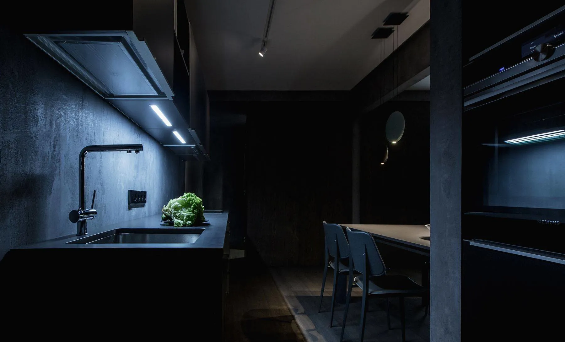 Modern minimalist kitchen with metallic surfaces and black countertops.