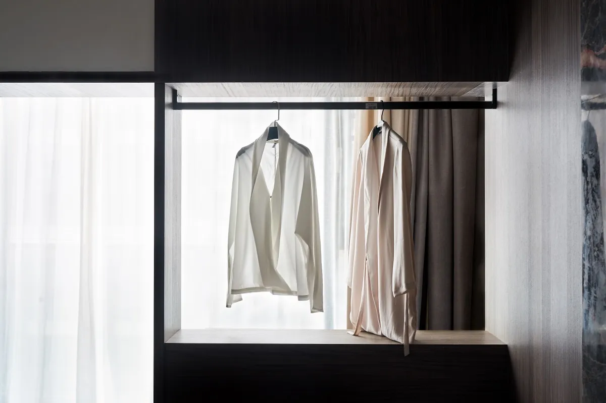 White blouses hanging on a clothing rack in a minimalist interior design setting.