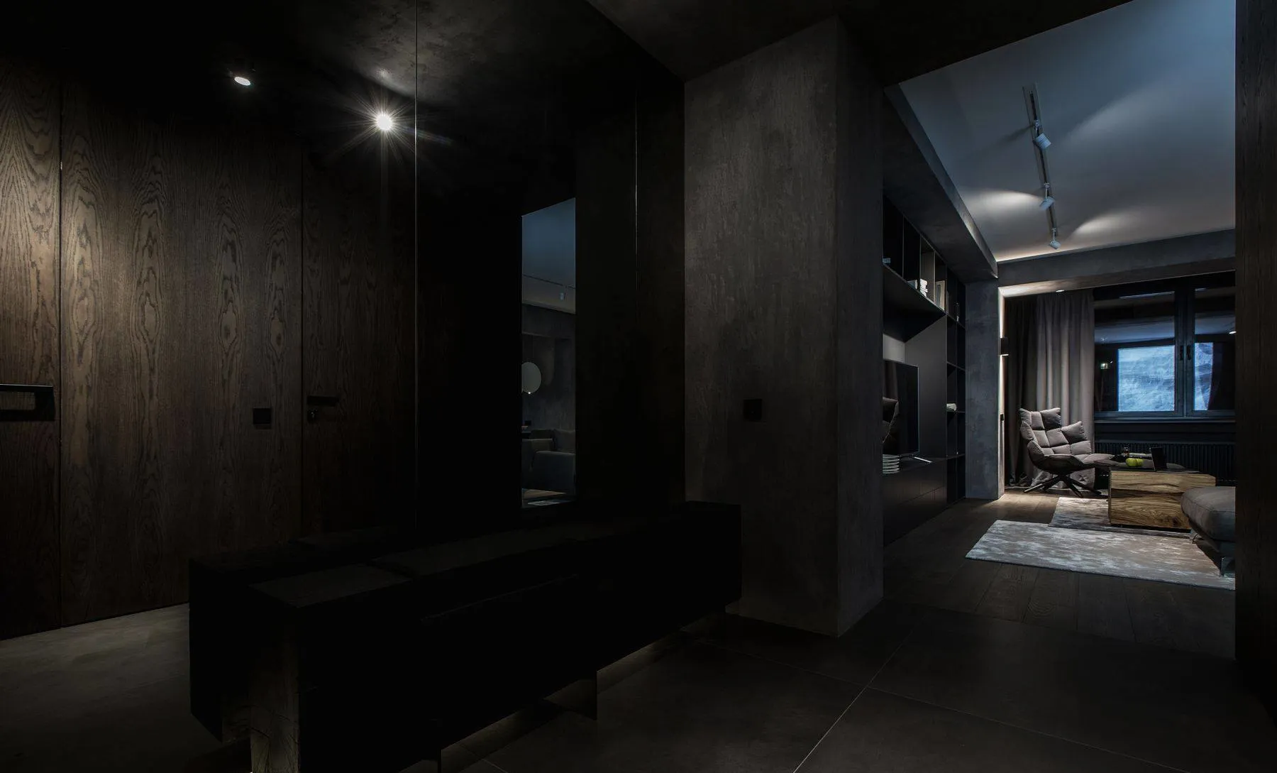 A modern living room with dark concrete walls and minimalist furniture.