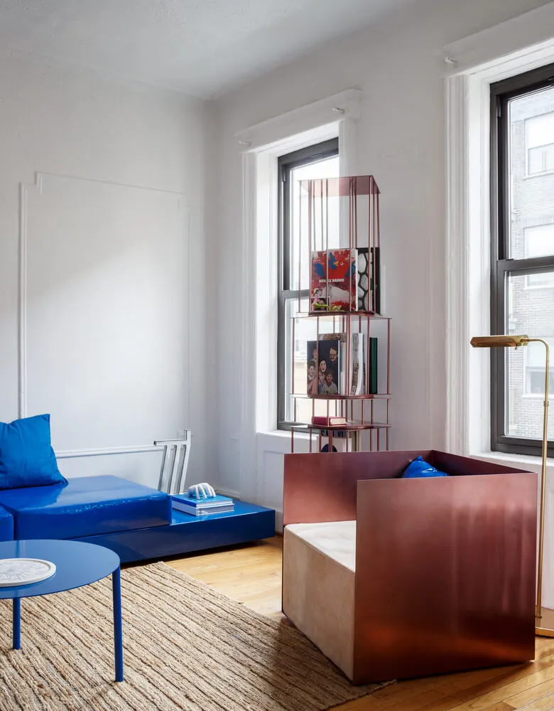 A modern living room featuring a metal shelving unit and a blue lounge chair.