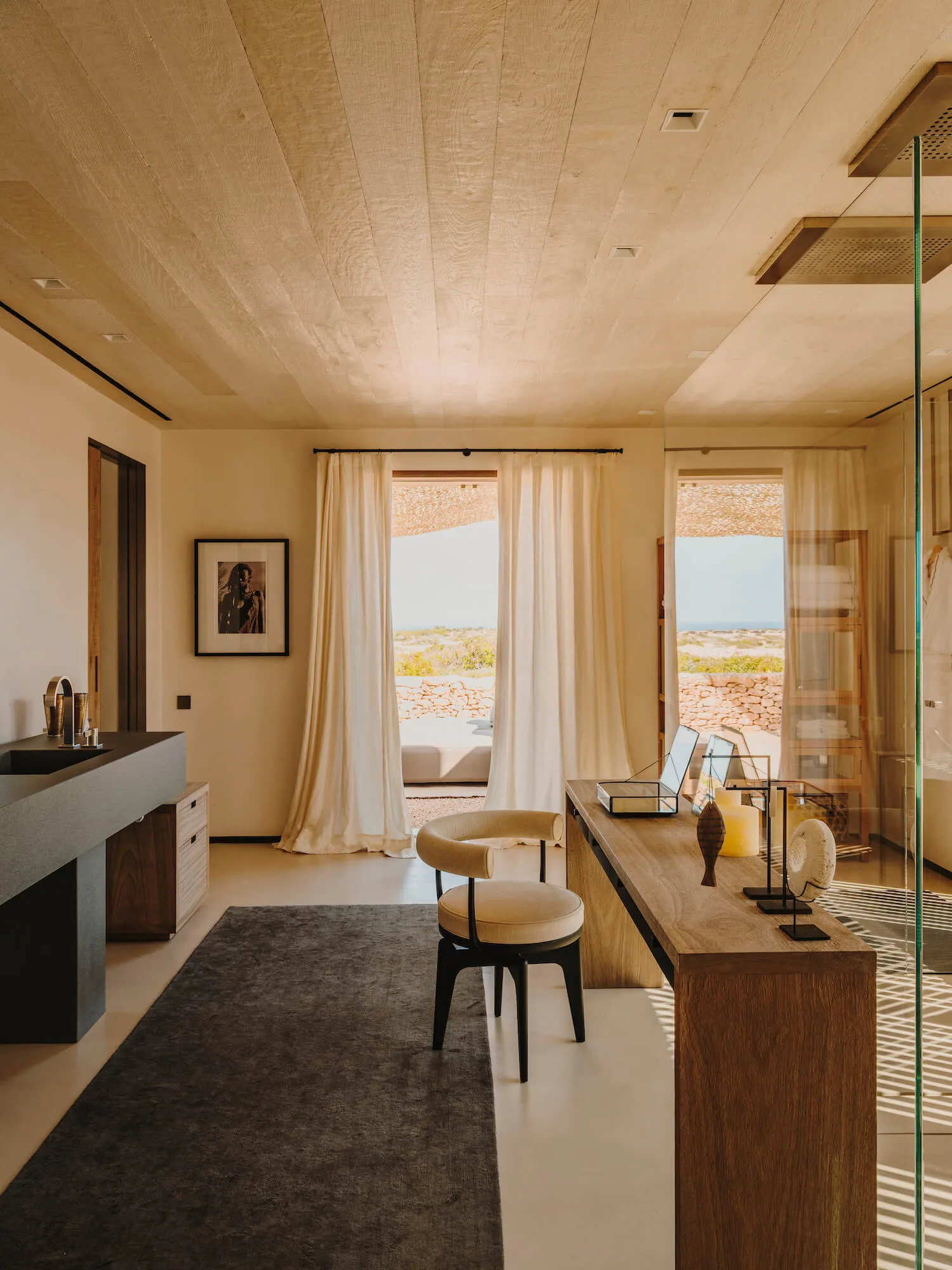 A minimalist bedroom with wood and frosted glass finishes and a large window overlooking natural scenery.